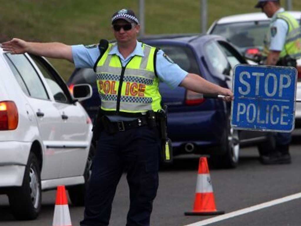 A police officer stationed on the road, holding a stop sign.