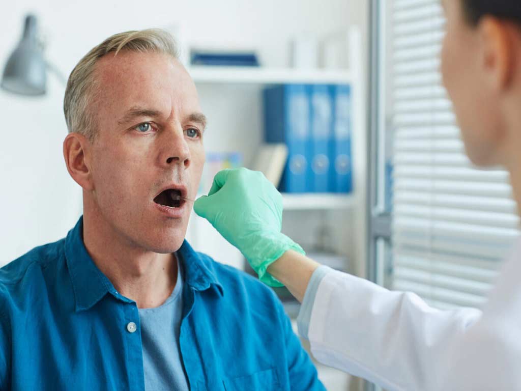 A professional conducting a saliva test on a male individual.