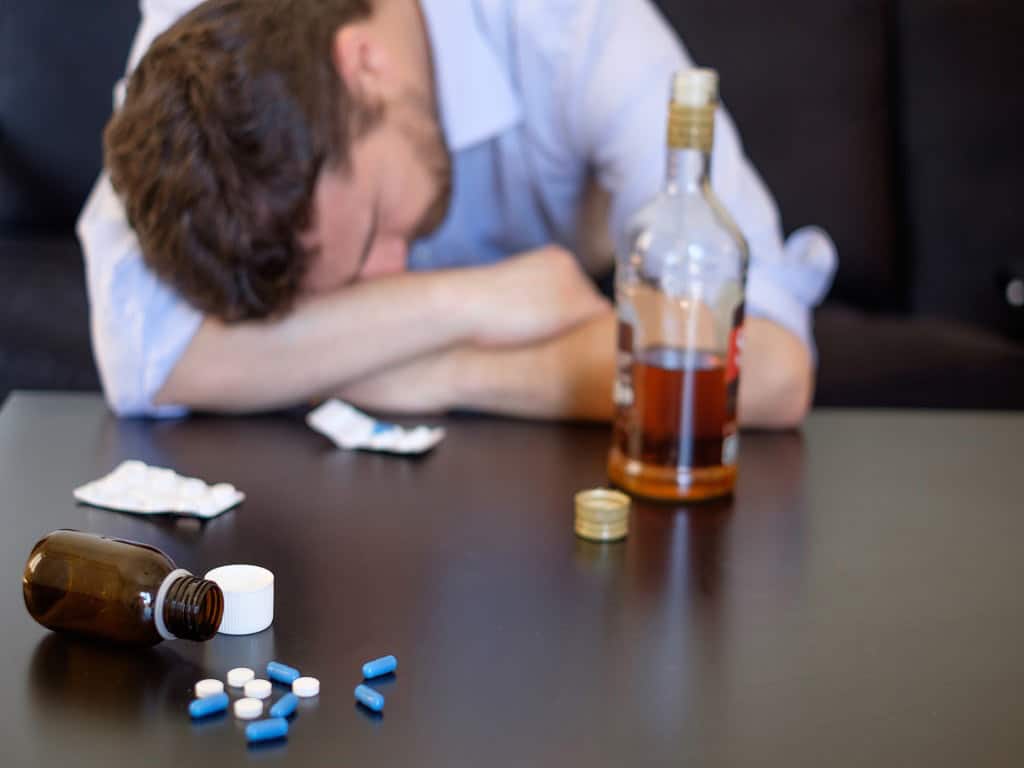 A man sleeping with pills and alcohol in front