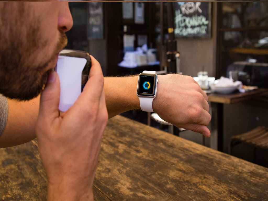 A man using a breathalyser and checking the results on his smartwatch
