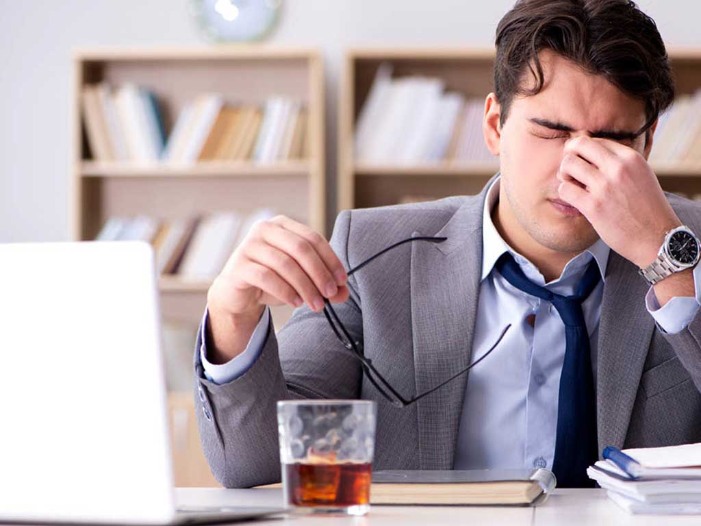 A male employee having a headache while drinking alcohol