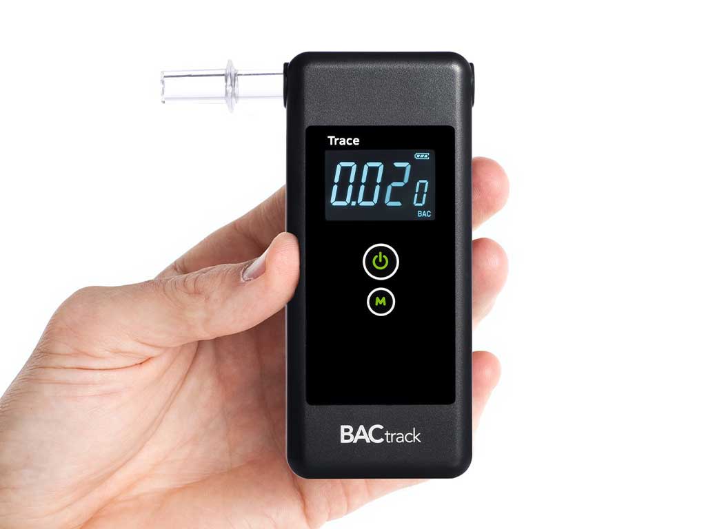 A person holding a breathalyzer while it shows the result