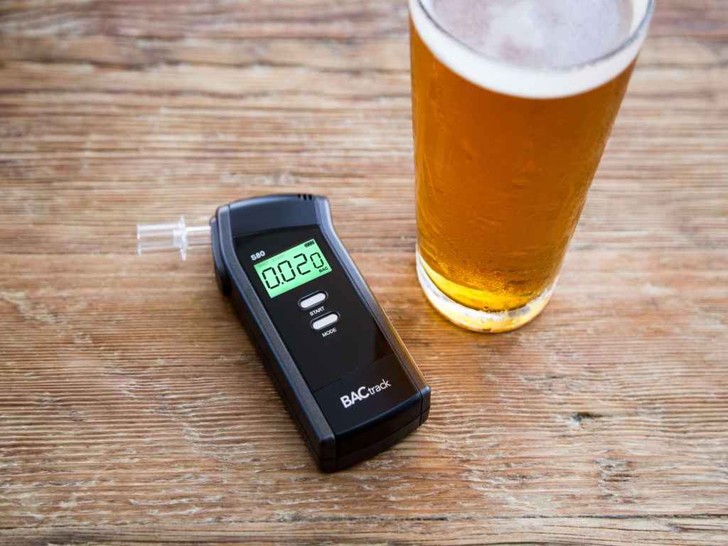 A breathalyzer next to an alcoholic beverage
