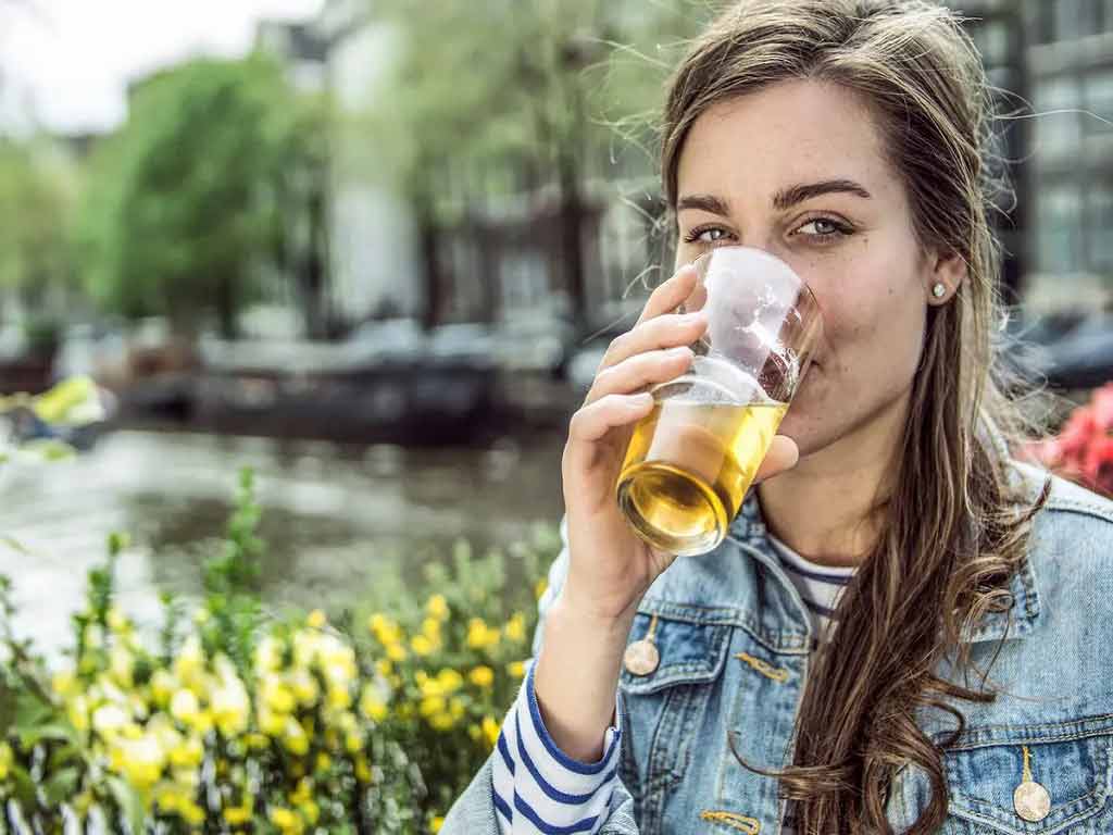 A woman drinking an alcoholic beverage outdoors