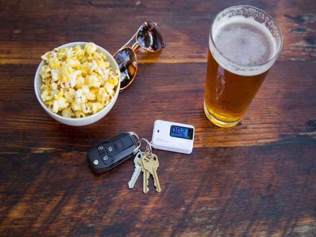 A keychain breathalyser, food and glass of beer on the table