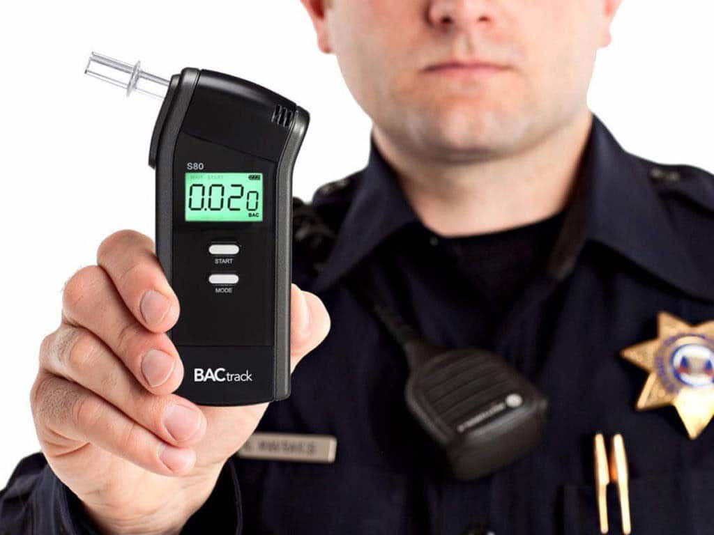 A police officer holding a breathalyzer
