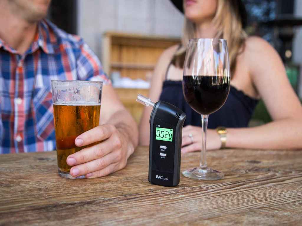 A man and woman drinkig with a breathalyzer in front