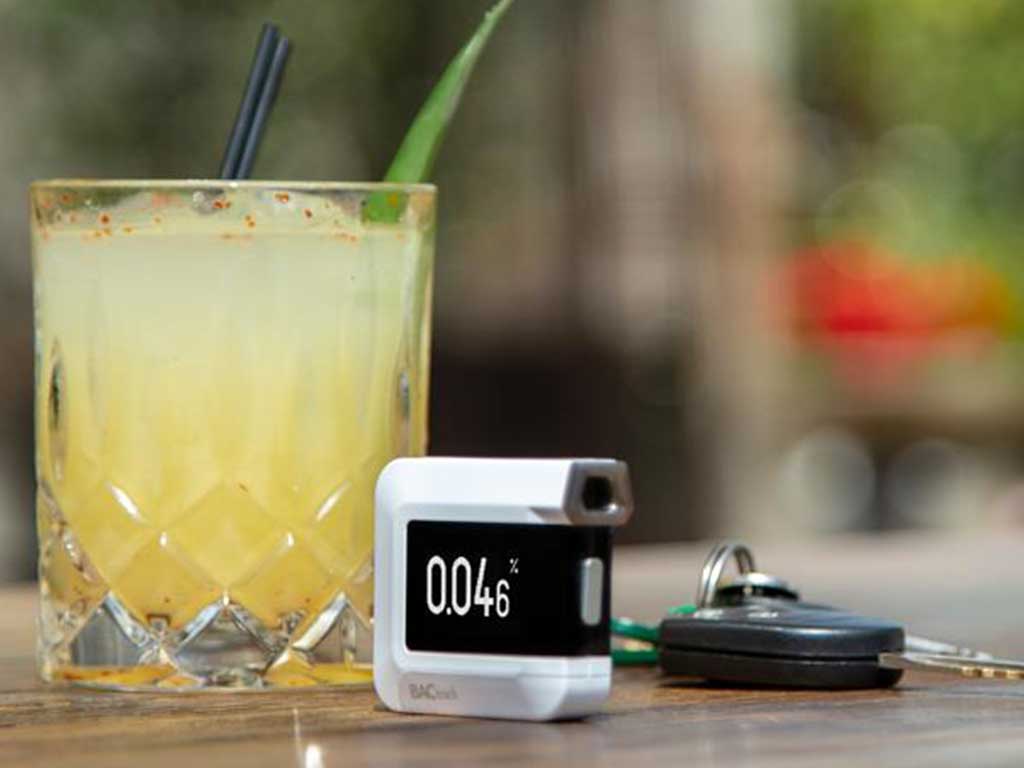 A drink, breath tester, and keys on a table
