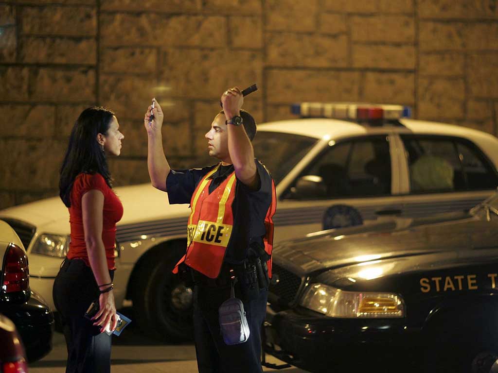 A police officer conducting a field sobriety test on a female driver