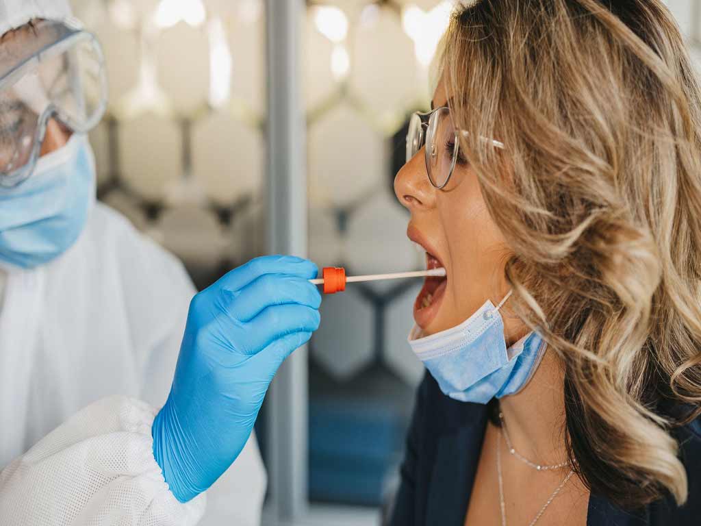 A professional getting a saliva sample from a female patient