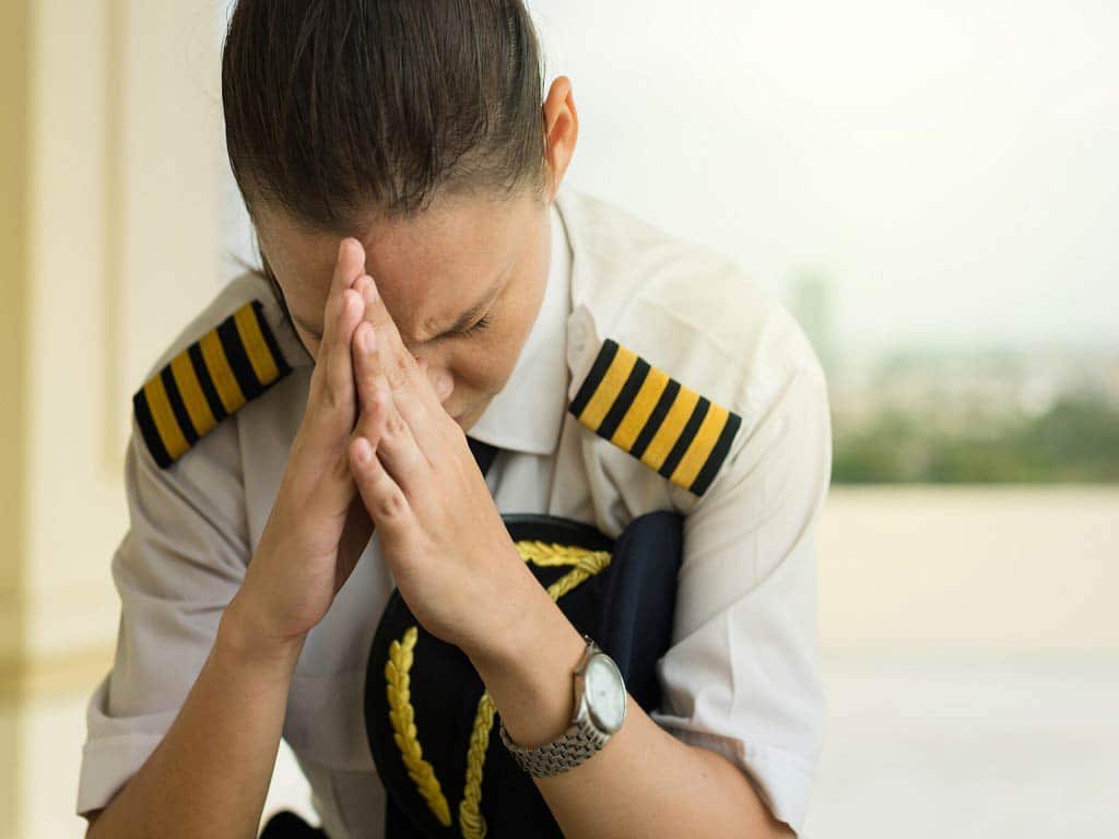 A female pilot sitting with her hands on her face