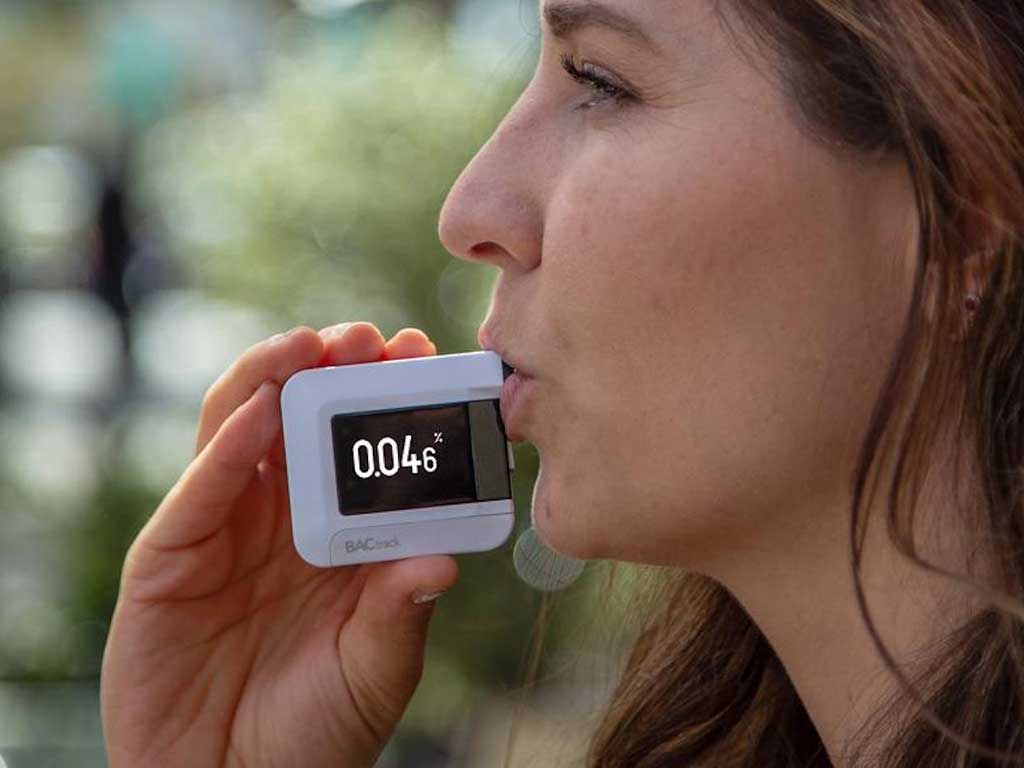 A woman using a personal breathalyser.