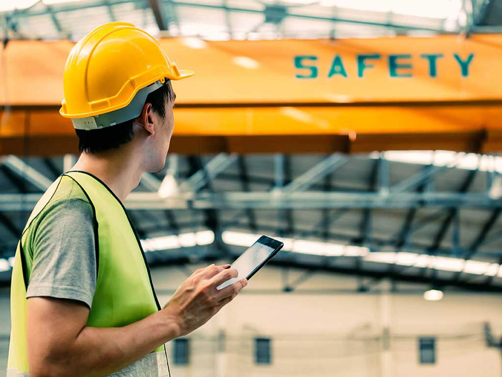 An employee looking at heavy machinery while holding a tablet