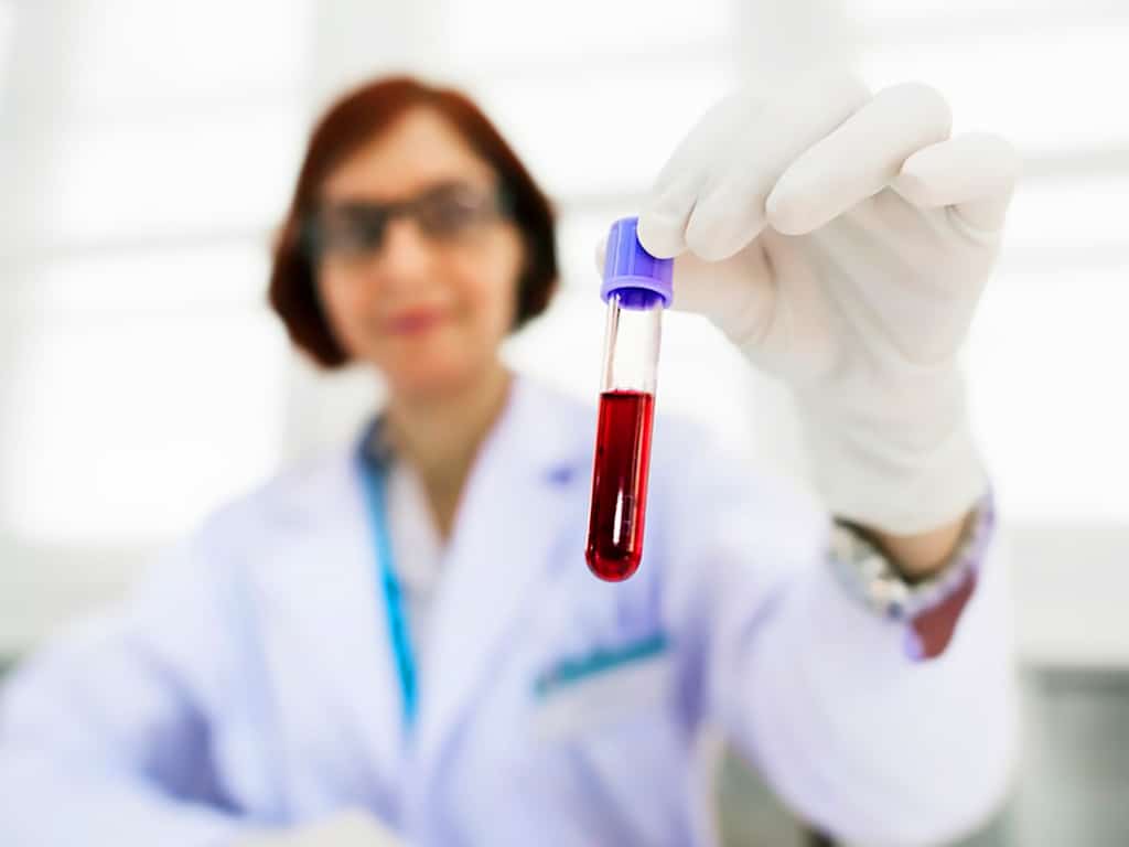 A professional holding a vial of blood