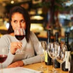 A woman drinking a glass of wine at a restaurant