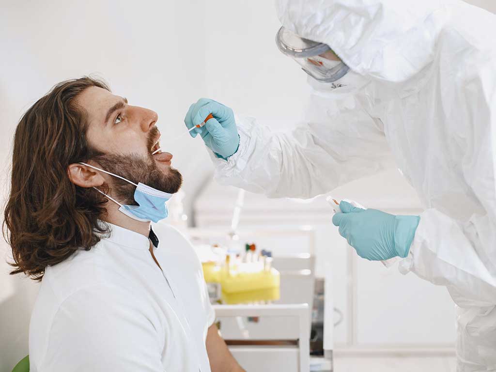 A lab technician conducting a saliva test on a male patient