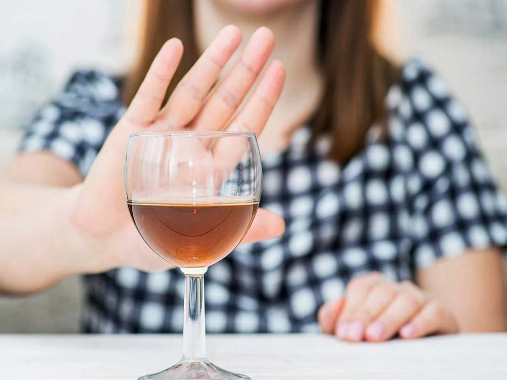 A woman gesturing no to an alcoholic beverage