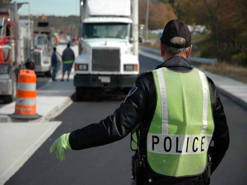A police officer signaling a truck driver to stop for inspection