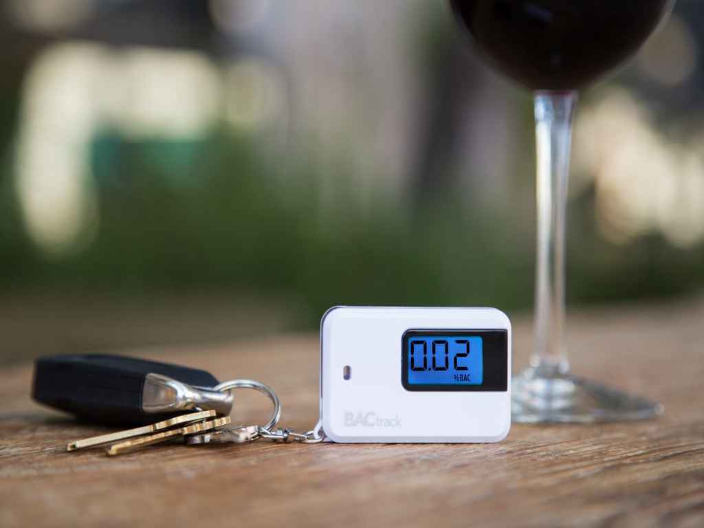 The BACtrack Go Keychain with a glass of alcohol on the table